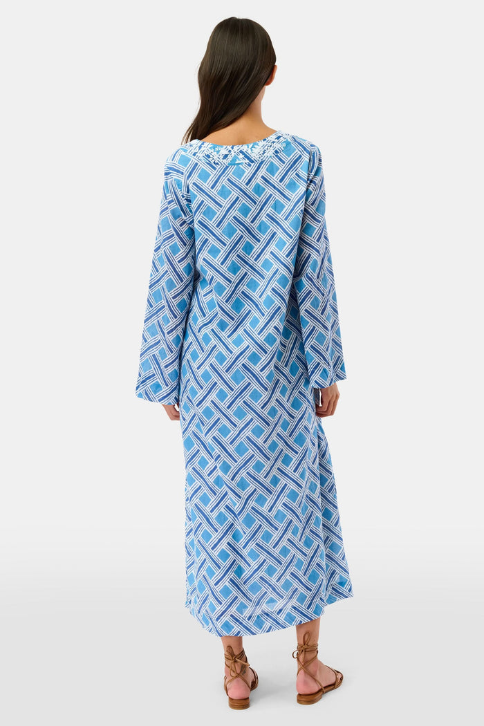A woman stands in sandals against a white background wearing the Roller Rabbit Liana Astrella Kurta, a blue and white patterned, maxi-length cotton kurta with a V-neck and ruffle detailing.