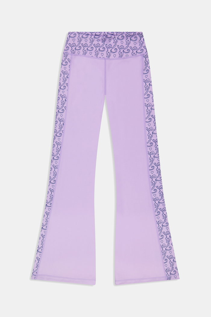 A person wears Roller Rabbit’s Lovely Monkey Ally Flared Leggings—lavender with a patterned waistband and side panels—paired with white sneakers, standing against a plain white background.