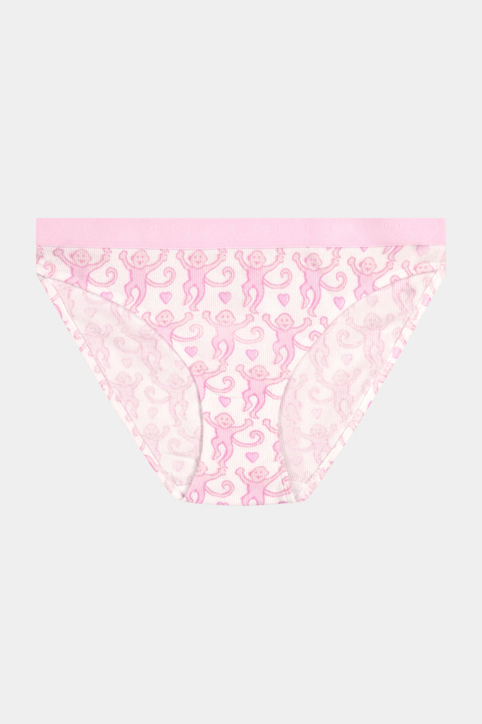 A person wears a light pink pima modal bra and the Roller Rabbit Lovely Monkey Hudson Bikini panty with a cheeky monkey print, standing with hands on hips against a plain background.