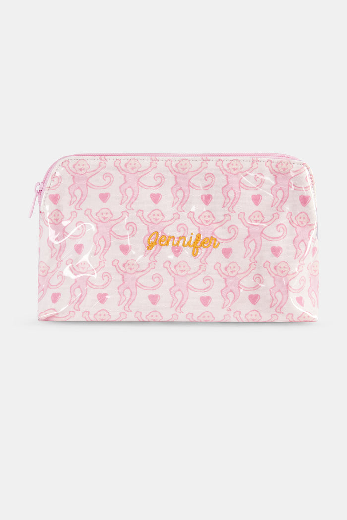 The Lovely Monkey Makeup Bag by Roller Rabbit is a rectangular white cotton canvas pouch with a pink zipper, featuring a repeating pattern of pink cartoon monkeys and small pink hearts.