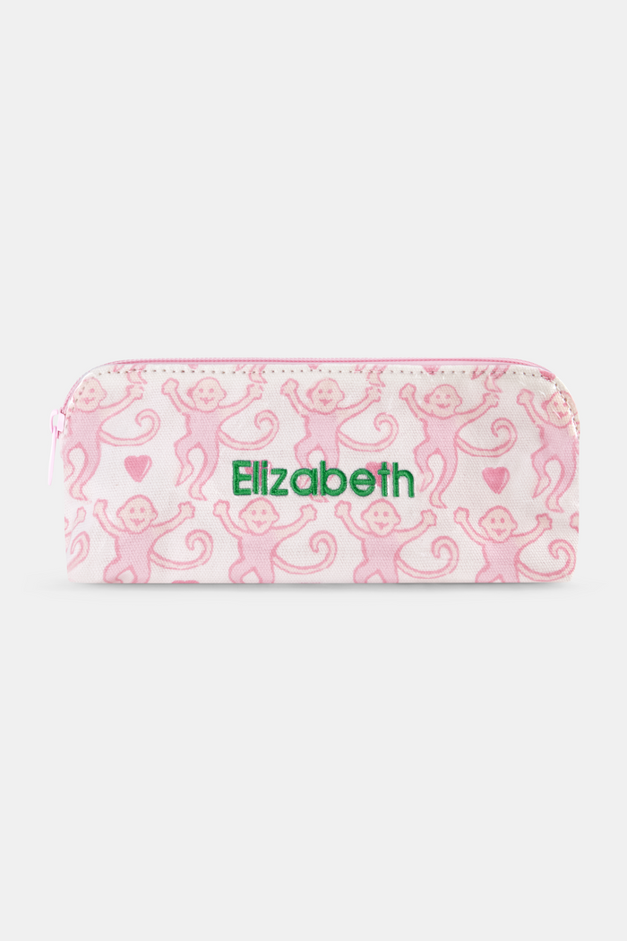 The Lovely Monkey Makeup Bag by Roller Rabbit is a rectangular white cotton canvas pouch with a pink zipper, featuring a repeating pattern of pink cartoon monkeys and small pink hearts.