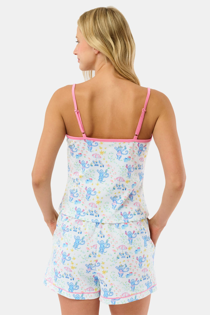 A blonde woman wears the Roller Rabbit May Flowers Mischa Set, a soft Pima cotton pajama with blue cartoon prints, pink trim, and cheerful patterns. The sleeveless top and loose shorts provide cozy comfort.
