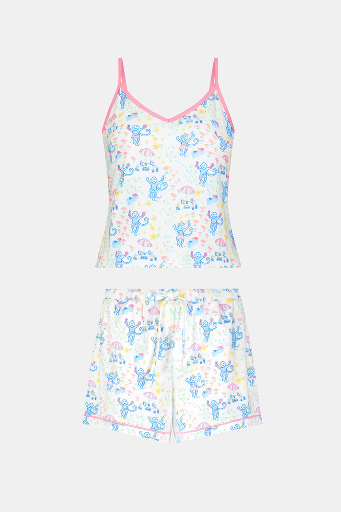 A blonde woman wears the Roller Rabbit May Flowers Mischa Set, a soft Pima cotton pajama with blue cartoon prints, pink trim, and cheerful patterns. The sleeveless top and loose shorts provide cozy comfort.