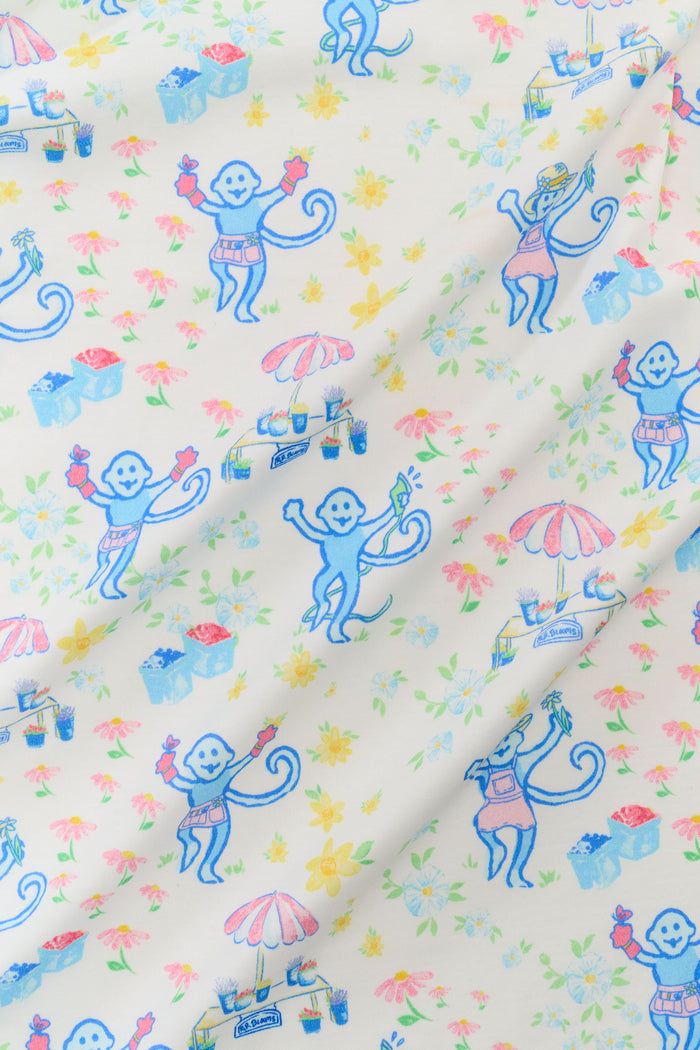 A woman in Roller Rabbit's May Flowers Fiora Pajamas—featuring a floral print, short sleeves, and long pants—stands barefoot against a plain white background.