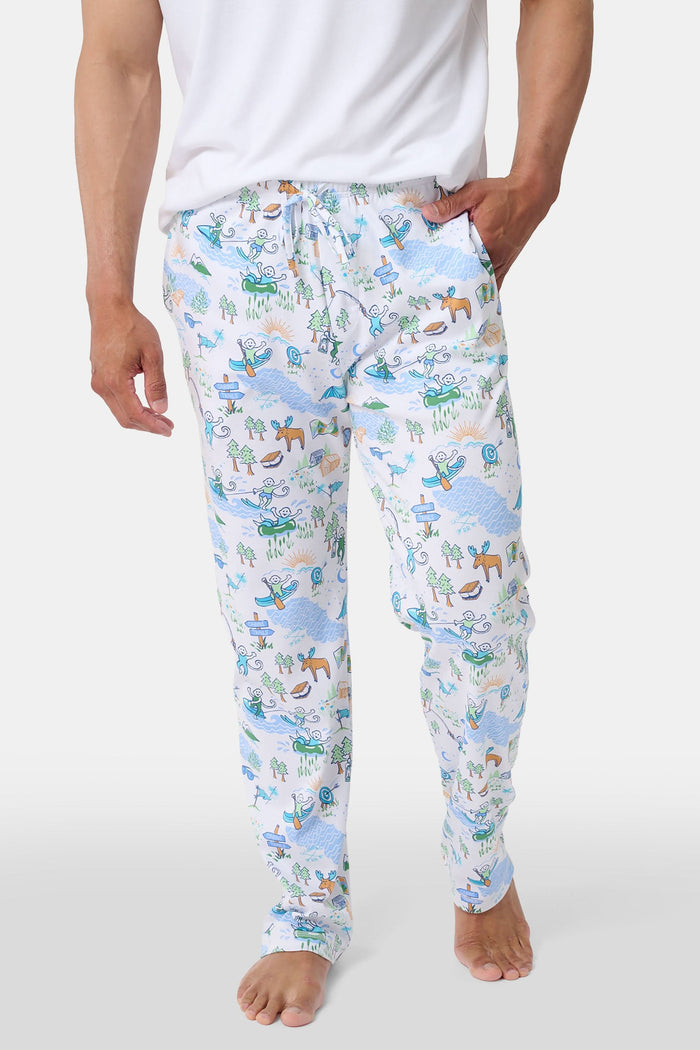 A person wears the Roller Rabbit Mens Camp RR Simon Pant, featuring a colorful animal and nature print, with hands in pockets and a plain white shirt. The barefoot individual stands against a white background.