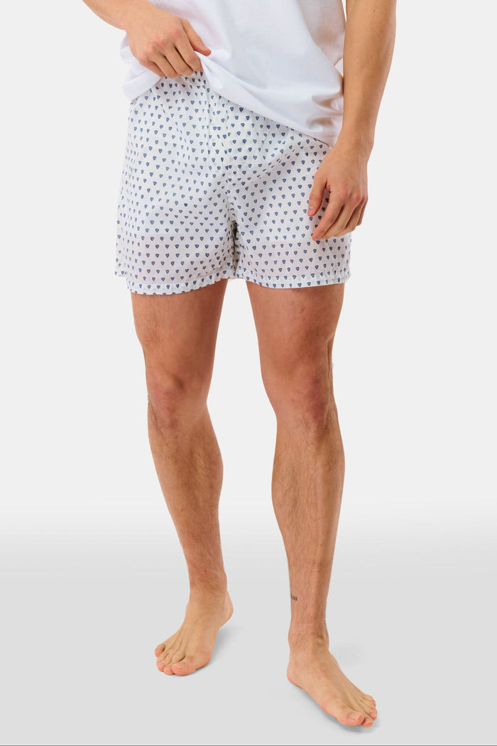 Wearing the Roller Rabbit Mens Hearts Boxer Set, which includes a white T-shirt and breathable cotton boxers with a hearts print, a person stands barefoot against a plain white background.