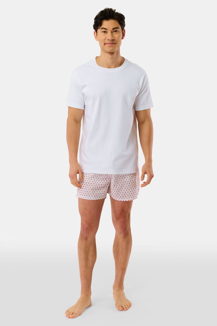 Wearing the Roller Rabbit Mens Hearts Boxer Set, which includes a white T-shirt and breathable cotton boxers with a hearts print, a person stands barefoot against a plain white background.