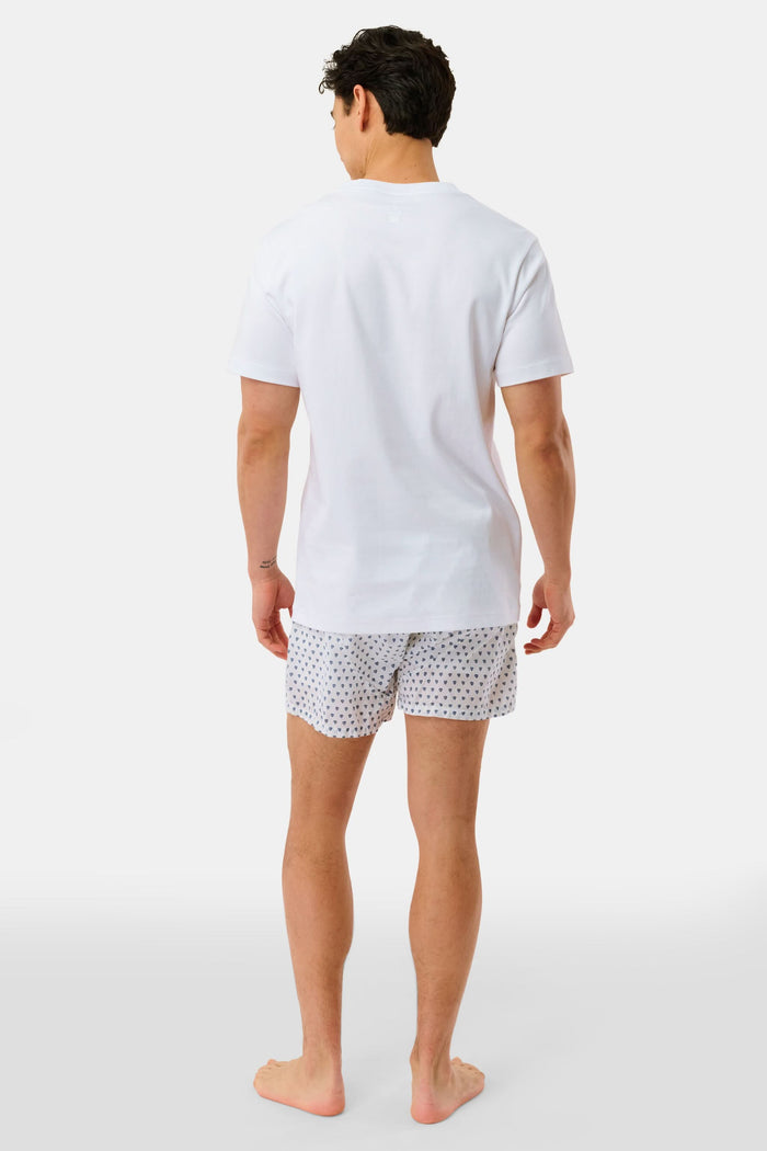 Wearing the Roller Rabbit Mens Hearts Boxer Set, which includes a white T-shirt and breathable cotton boxers with a hearts print, a person stands barefoot against a plain white background.