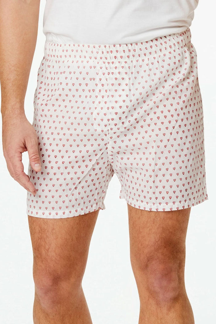 Wearing the Roller Rabbit Mens Hearts Boxer Set, which includes a white T-shirt and breathable cotton boxers with a hearts print, a person stands barefoot against a plain white background.
