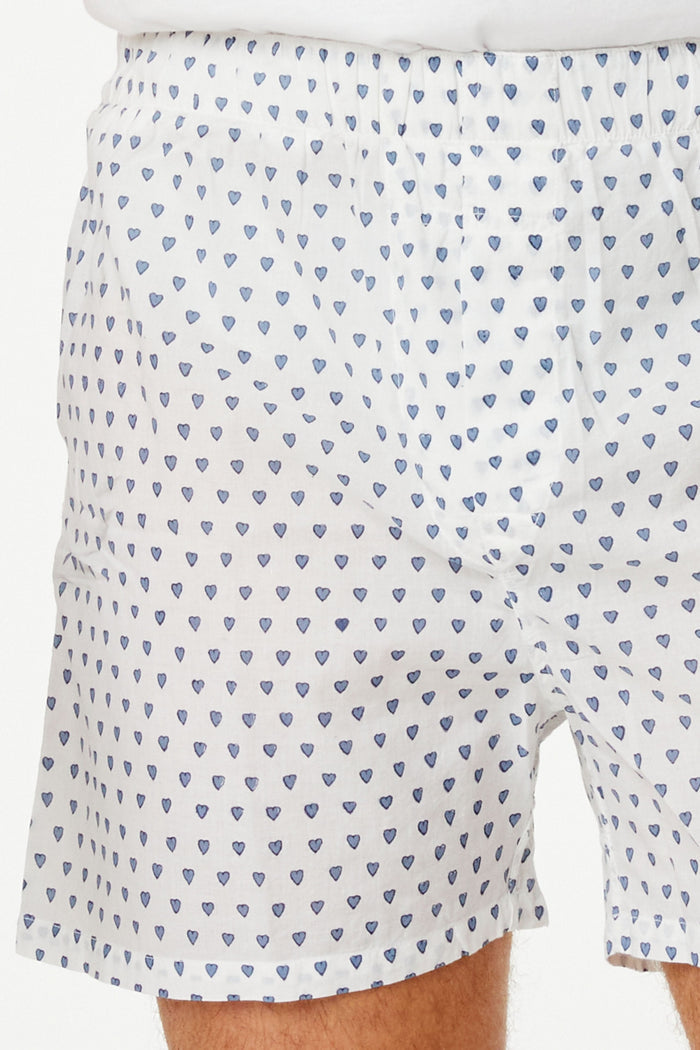 Wearing the Roller Rabbit Mens Hearts Boxer Set, which includes a white T-shirt and breathable cotton boxers with a hearts print, a person stands barefoot against a plain white background.