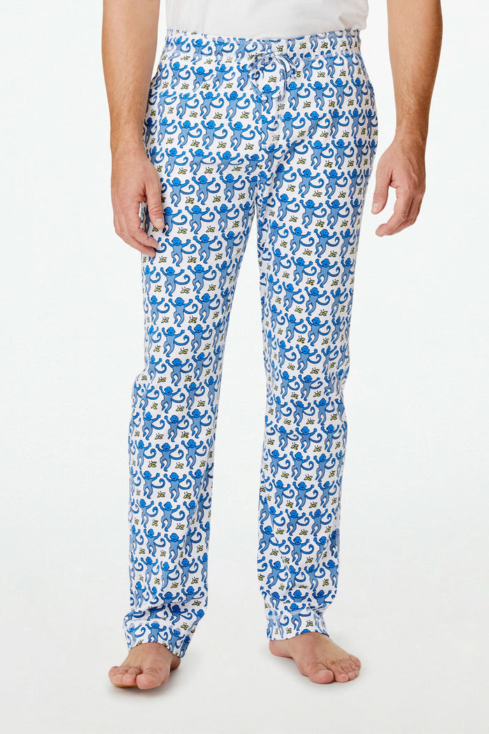 A person stands barefoot against a plain white background, showing only the lower half of their body while wearing Roller Rabbit Mens Monkey Simon Pant pajama pants.