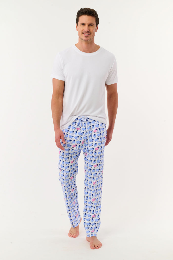 A person models the lower half of the Roller Rabbit Mens Sammy The Sheep Simon Pant—a relaxed fit PJ pant featuring a blue and pink sheep print—while standing barefoot on a white background.