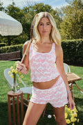 A woman stands outdoors holding a tennis racket and wearing the Roller Rabbit Minnows Astor Tank, paired with matching shorts in a grassy yard with chairs, a table with flowers, and trees in the background.