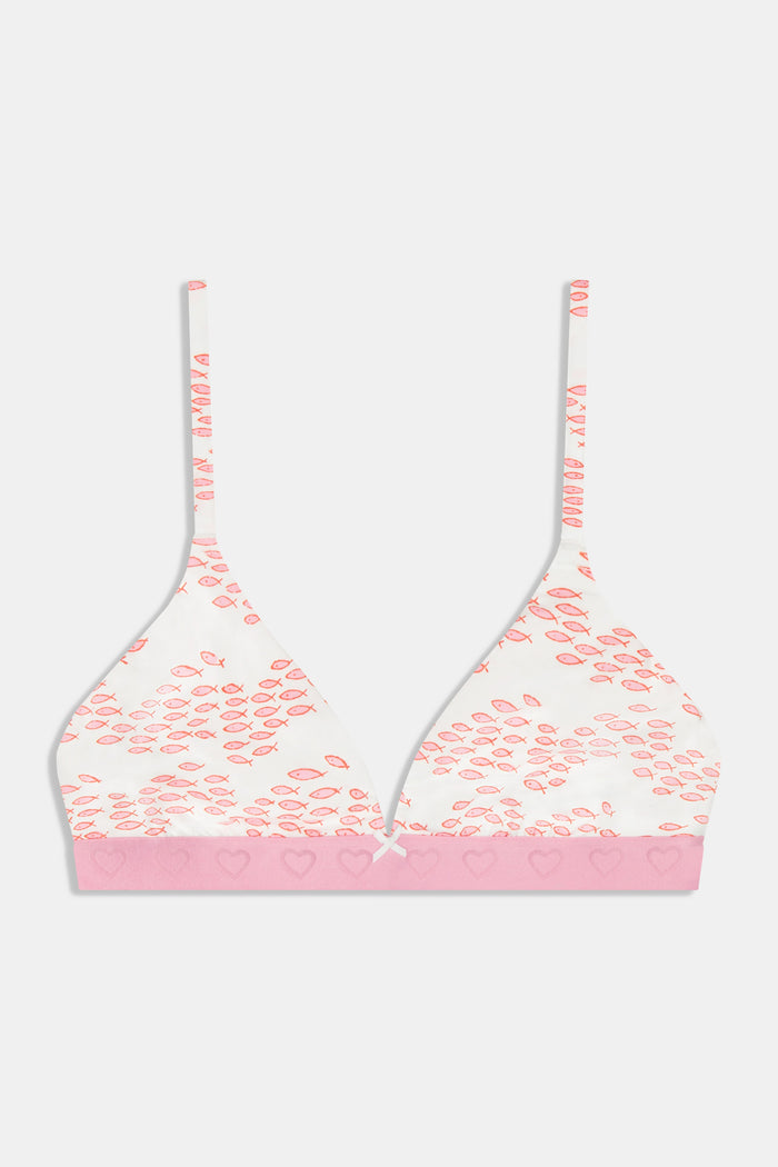 A woman wears the Roller Rabbit Minnows York Bralette, featuring a white cotton-modal blend with a pink fish print, pink trim, and adjustable straps, shown from shoulders to waist against a plain background.