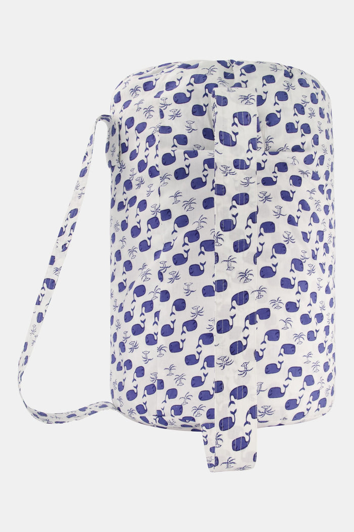 The Moby Sleepover Bag by Roller Rabbit is a large, white, cylindrical cotton bag with a blue whale pattern and a clear front pocket labeled "Sleepover!" It's soft and ideal for carrying bedding or sleepover essentials.