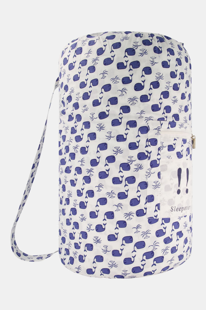 The Moby Sleepover Bag by Roller Rabbit is a large, white, cylindrical cotton bag with a blue whale pattern and a clear front pocket labeled "Sleepover!" It's soft and ideal for carrying bedding or sleepover essentials.