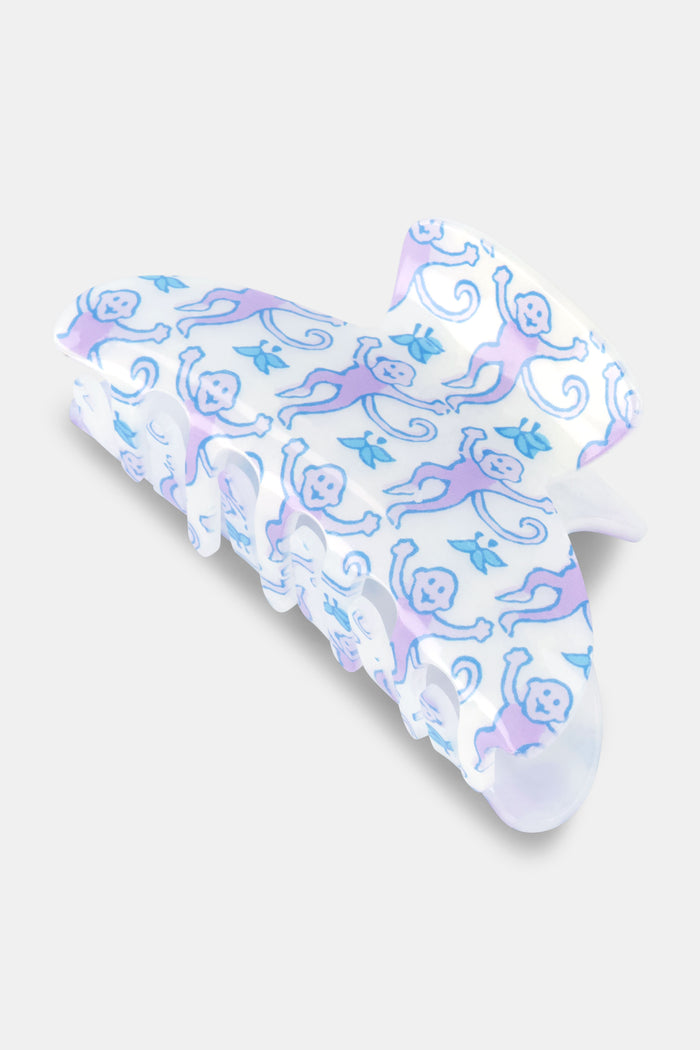 The Roller Rabbit Monkey Claw Clip adds a fun pop to your hair with playful purple and blue monkeys on a white pastel background—a cute and charming accessory for any collection.