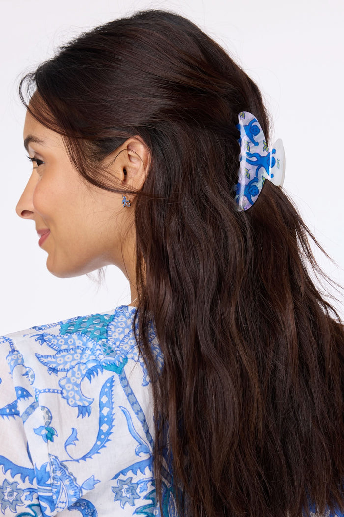 The Roller Rabbit Monkey Claw Clip is a white acrylic hair accessory featuring blue monkeys and small green leaves, displayed on a plain light gray background.