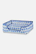 The Roller Rabbit Monkey Dog Bed is a rectangular plush bed with raised sides, a lowered front entrance, and a blue and white abstract pattern. It features machine-washable materials for easy cleaning.