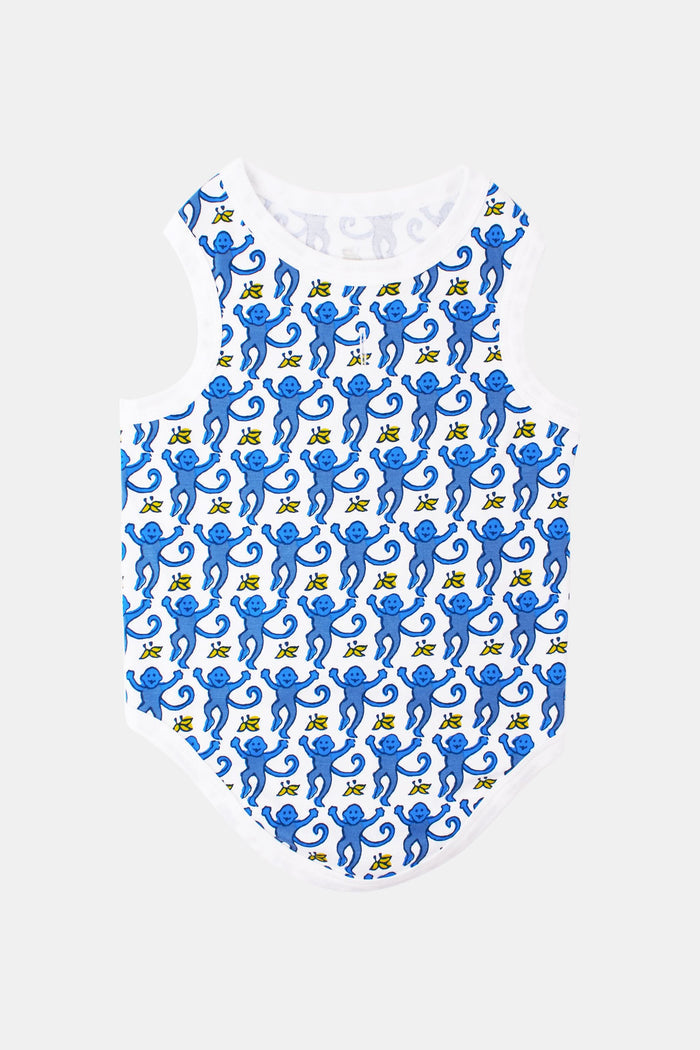 A brown curly-haired dog sits on a light surface, looking up with perked ears against a white background, wearing stylish blue and white Monkey Dog Pajamas by Roller Rabbit made from soft Pima cotton.