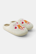 Roller Rabbit’s Monkey Fuzzy Slippers are cream-colored shearling slides with embroidered orange and white cats and red hearts on top, finished with a durable rubber sole.