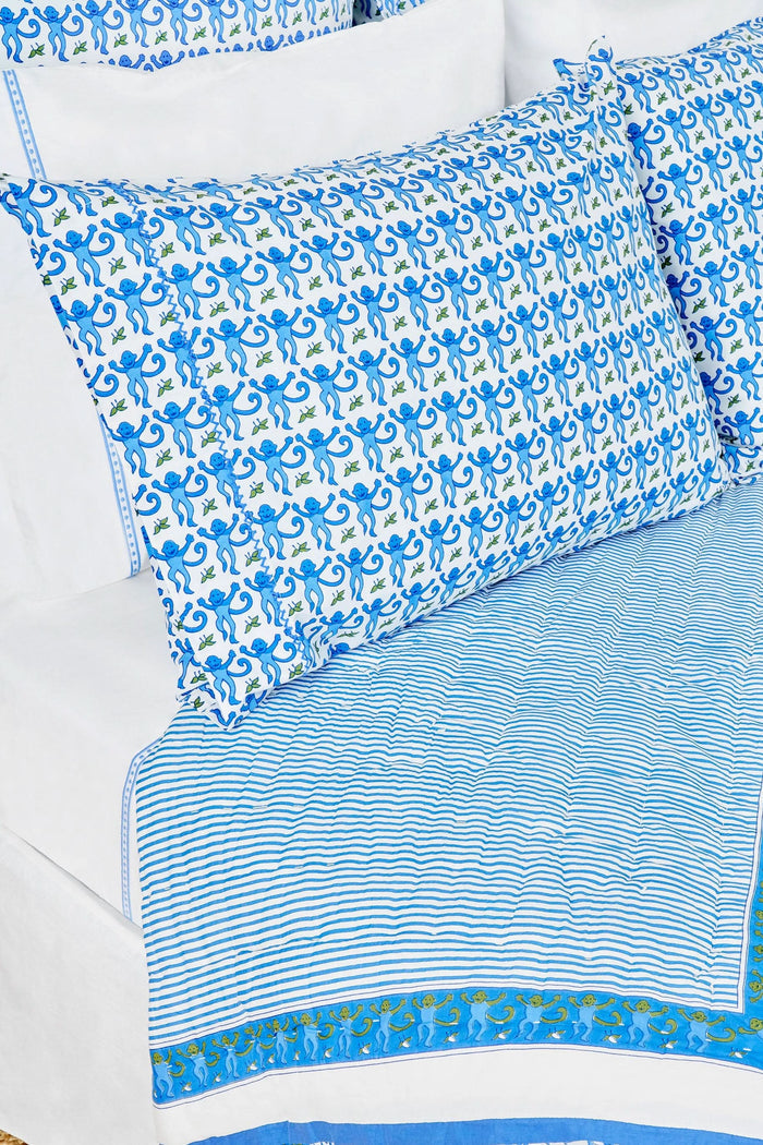 Two Monkey Pillowcase Set pillows by Roller Rabbit, featuring a blue and green floral pattern and 100 cotton pillowcases, are stacked on a white surface with a cream decorative screen in the background.