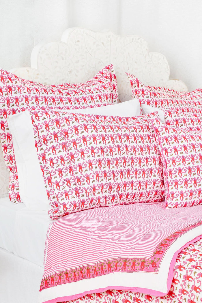 Two stacked pillows are covered with Roller Rabbit’s Monkey Pillowcase Set, featuring a playful pink monkey print with leaves. The whimsical pattern repeats across the entire surface, creating a charming and cheerful bedding look.