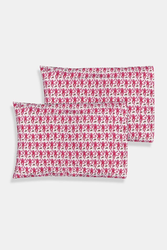 Two stacked pillows are covered with Roller Rabbit’s Monkey Pillowcase Set, featuring a playful pink monkey print with leaves. The whimsical pattern repeats across the entire surface, creating a charming and cheerful bedding look.