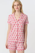 A woman with long blonde hair wears Roller Rabbit's Monkey Polo Pajamas—a matching polo-style top and bottom set—standing against a plain white background.