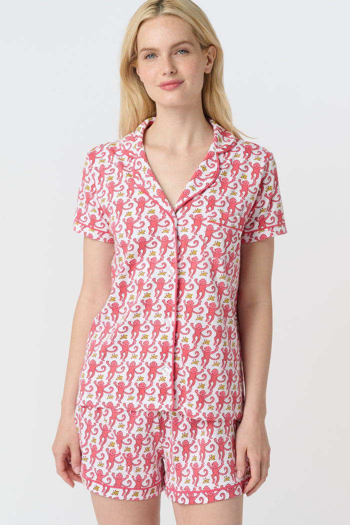 A woman with long blonde hair wears Roller Rabbit's Monkey Polo Pajamas—a matching polo-style top and bottom set—standing against a plain white background.