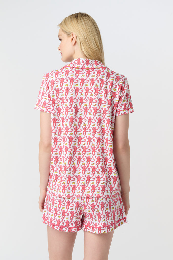 A woman with long blonde hair wears Roller Rabbit's Monkey Polo Pajamas—a matching polo-style top and bottom set—standing against a plain white background.