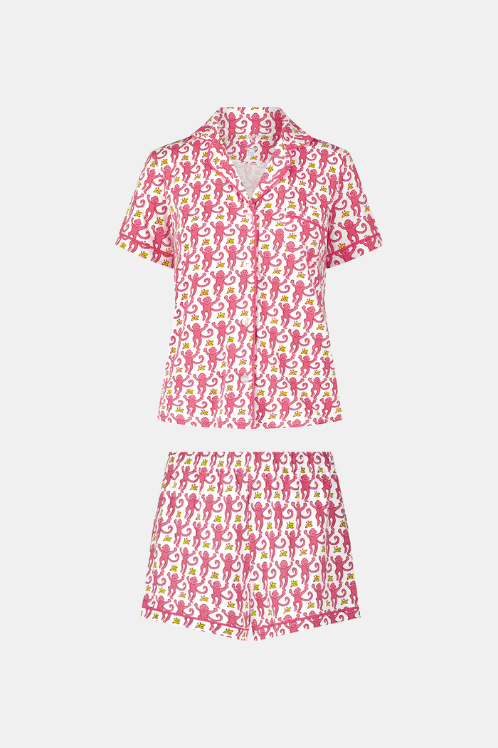 A woman with long blonde hair wears Roller Rabbit's Monkey Polo Pajamas—a matching polo-style top and bottom set—standing against a plain white background.