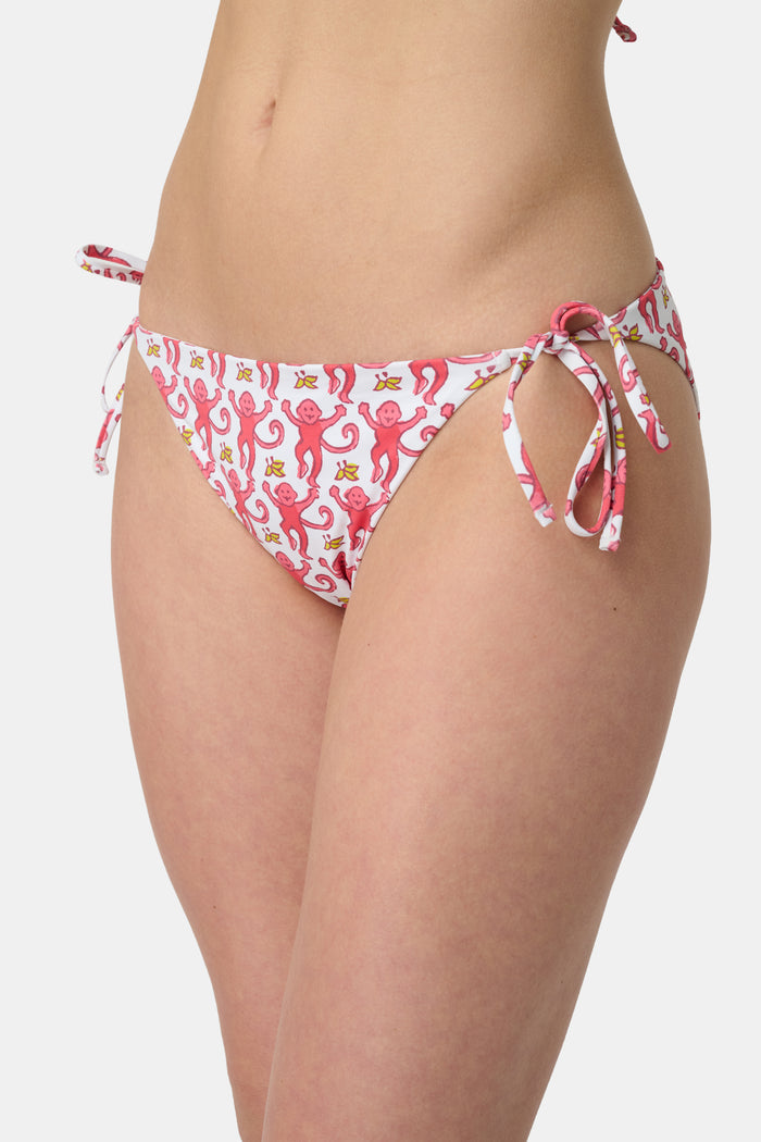 A person wears Roller Rabbit's Monkey/Hearts Serena Bikini Bottom, shown from mid-torso to upper thigh against a white background. These reversible bikini bottoms provide UPF 50+ sun protection.