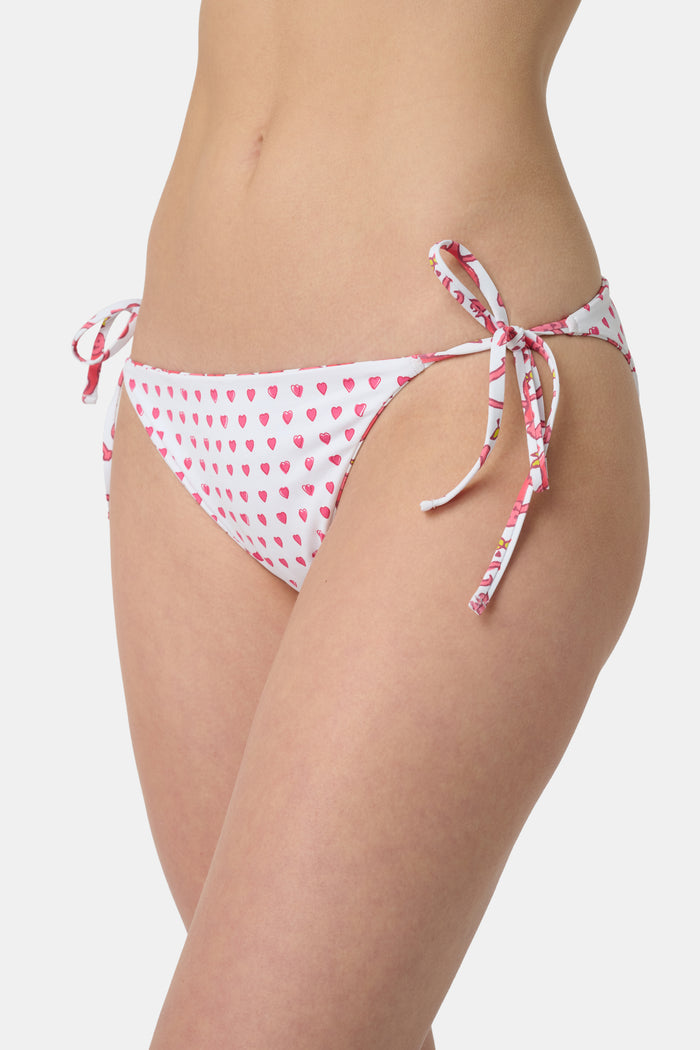 A person wears Roller Rabbit's Monkey/Hearts Serena Bikini Bottom, shown from mid-torso to upper thigh against a white background. These reversible bikini bottoms provide UPF 50+ sun protection.