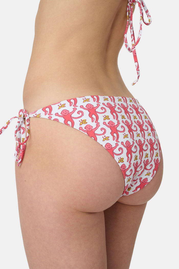 A person wears Roller Rabbit's Monkey/Hearts Serena Bikini Bottom, shown from mid-torso to upper thigh against a white background. These reversible bikini bottoms provide UPF 50+ sun protection.