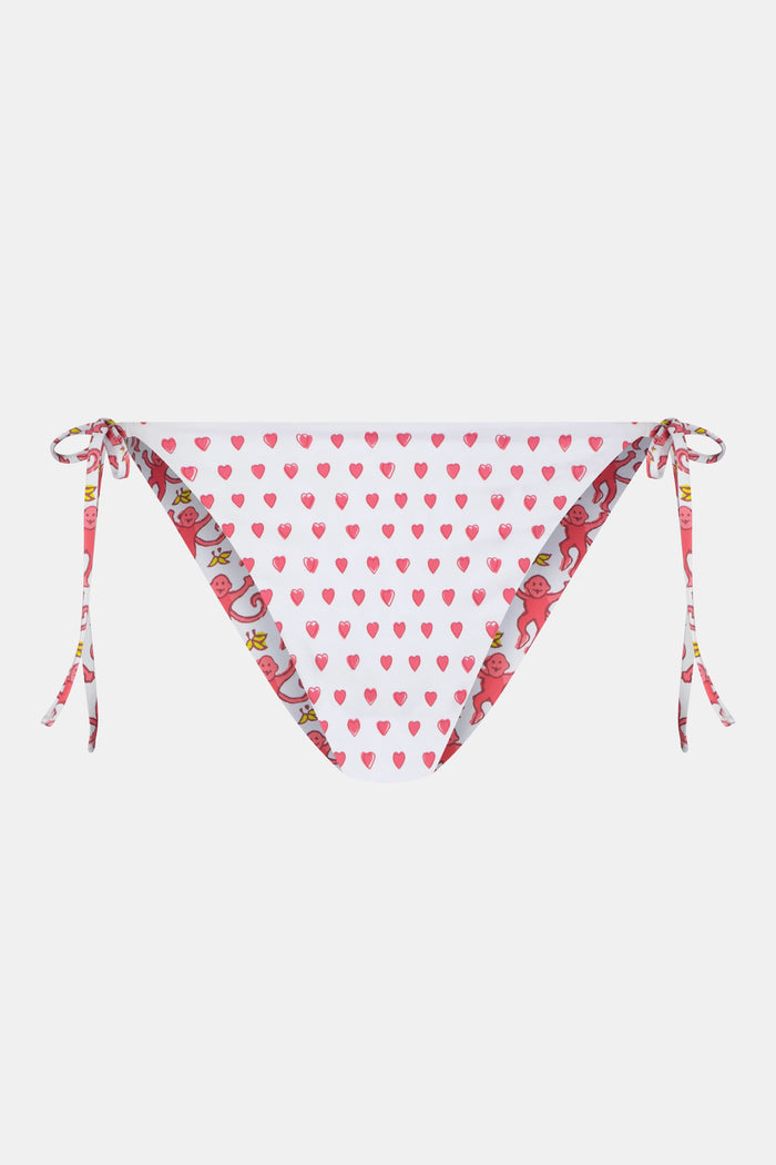 A person wears Roller Rabbit's Monkey/Hearts Serena Bikini Bottom, shown from mid-torso to upper thigh against a white background. These reversible bikini bottoms provide UPF 50+ sun protection.