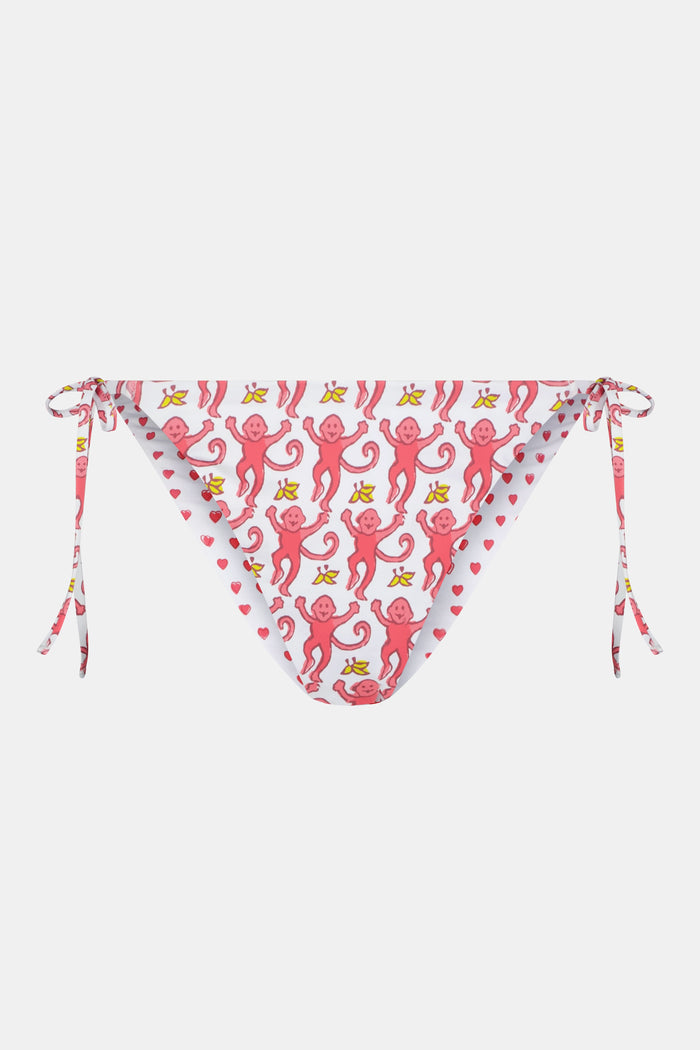 A person wears Roller Rabbit's Monkey/Hearts Serena Bikini Bottom, shown from mid-torso to upper thigh against a white background. These reversible bikini bottoms provide UPF 50+ sun protection.