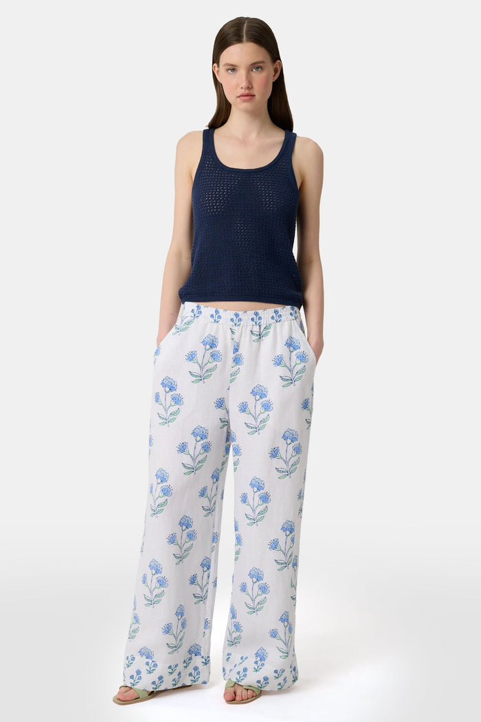 A woman wears the Roller Rabbit Pointelle Sasha Sweater Tank in navy with a textured open-weave design, paired with white shorts featuring blue floral prints. She is shown from shoulders to waist, looking slightly to the side.