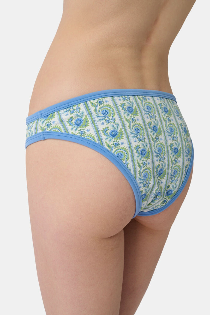 A person shown from the waist to upper thighs is wearing the Roller Rabbit Provencal Stripe Oceana Bikini Bottom featuring a blue and green floral design with light blue trim in a high-waisted bikini style.
