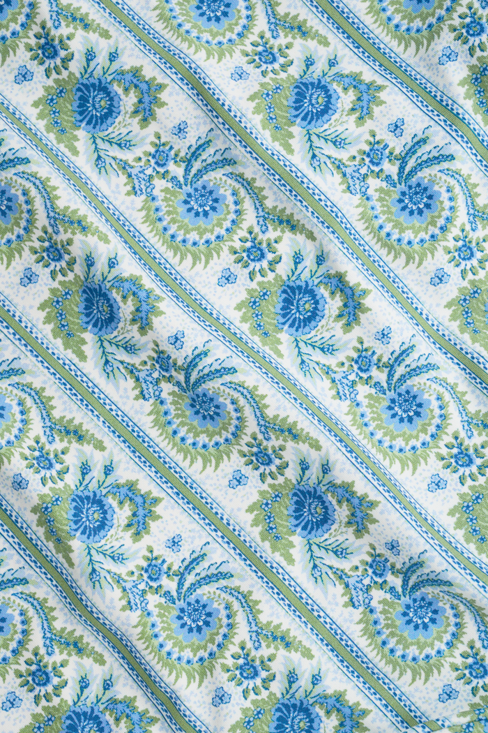 A person shown from the waist to upper thighs is wearing the Roller Rabbit Provencal Stripe Oceana Bikini Bottom featuring a blue and green floral design with light blue trim in a high-waisted bikini style.