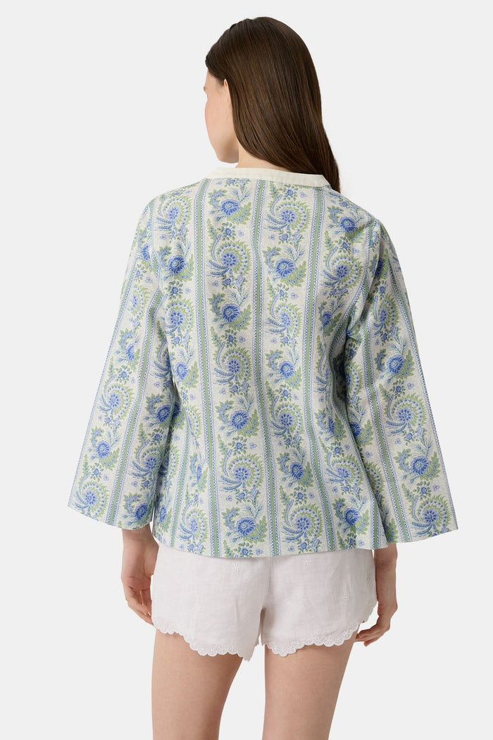 A woman models the Roller Rabbit Provencal Stripe Willow Tunic with blue and green floral patterns and a white V-neckline, paired with white scallop-hem shorts, against a plain light background.