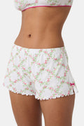 A person wearing Roller Rabbit Raspberry Garden Tara Shorts with a pink bow detail and a matching crop top, both in soft Pima Pointelle cotton, showing only their torso and upper thighs against a plain background.