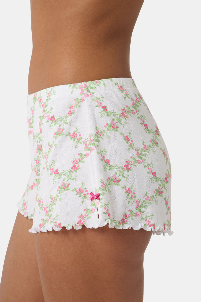 A person wearing Roller Rabbit Raspberry Garden Tara Shorts with a pink bow detail and a matching crop top, both in soft Pima Pointelle cotton, showing only their torso and upper thighs against a plain background.