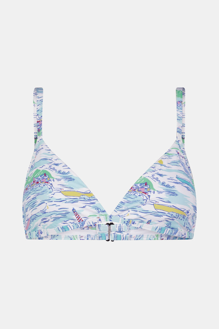 A woman with long brown hair smiles softly, wearing the Regatta Marais Bikini Top by Roller Rabbit in a nautical print, standing against a plain white background.