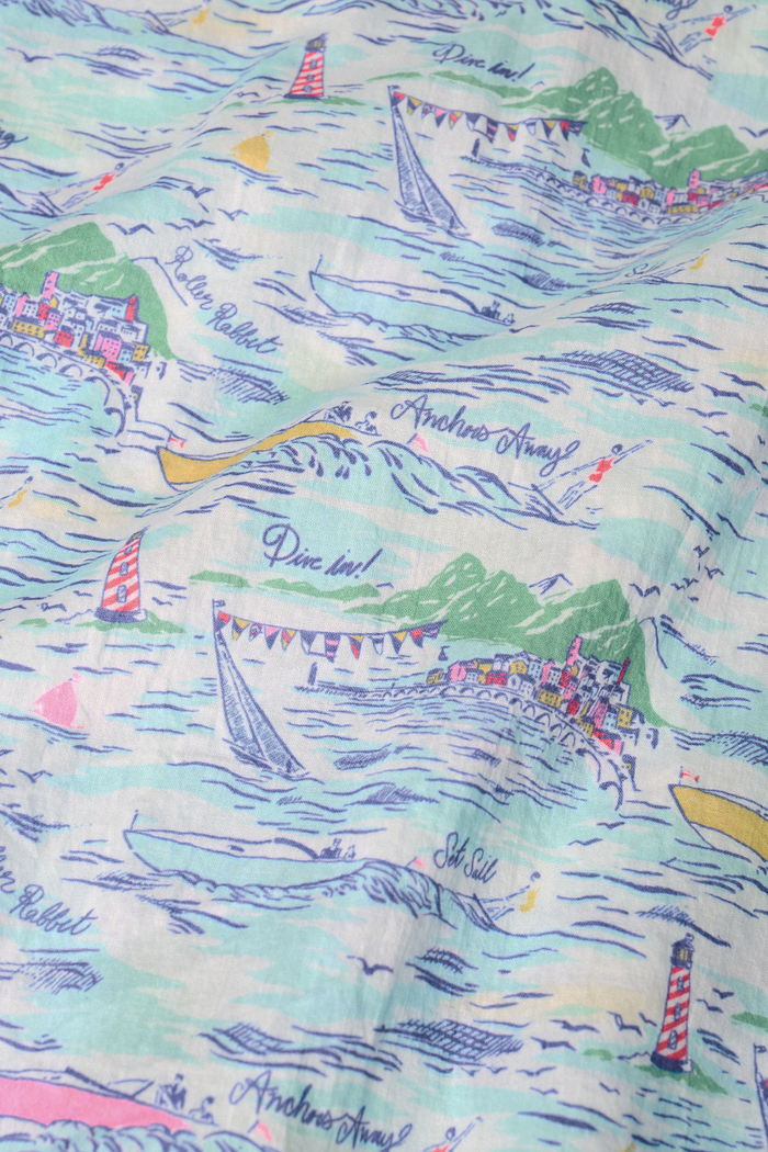 A woman wears the Roller Rabbit Regatta Preston Set, a cotton voile two-piece with a pastel coastal print, featuring a short-sleeve top with gathered neckline and matching shorts, standing against a plain white background.