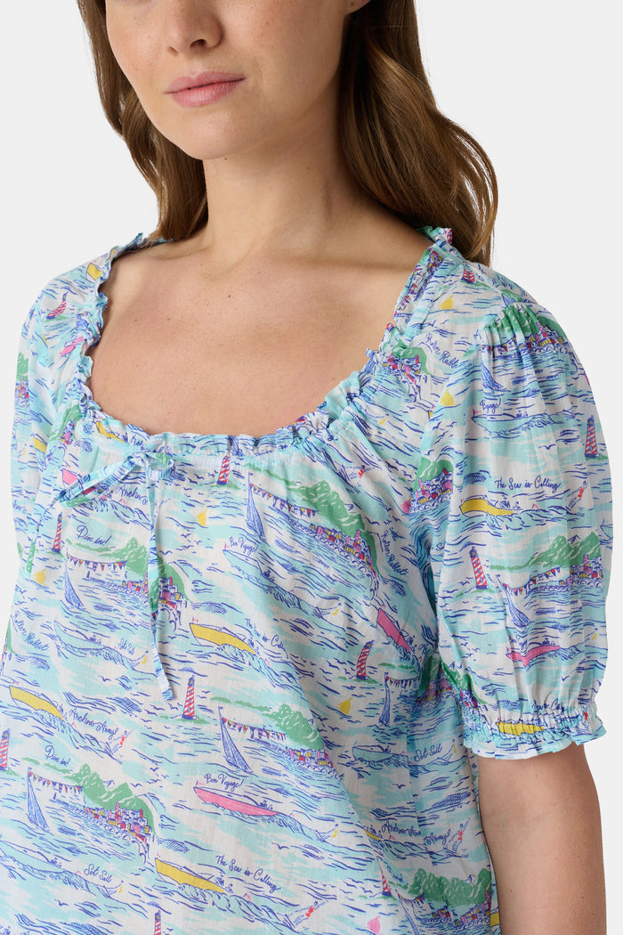 A woman wears the Roller Rabbit Regatta Preston Set, a cotton voile two-piece with a pastel coastal print, featuring a short-sleeve top with gathered neckline and matching shorts, standing against a plain white background.