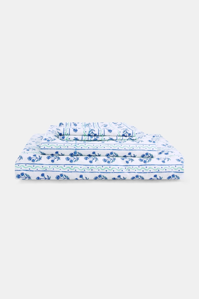 The Rosa Wavy Stripe Sheet Set by Roller Rabbit features a white sheet with blue floral print and green wavy stripes, ideal for twin XL beds or anyone seeking stylish cotton bedding.
