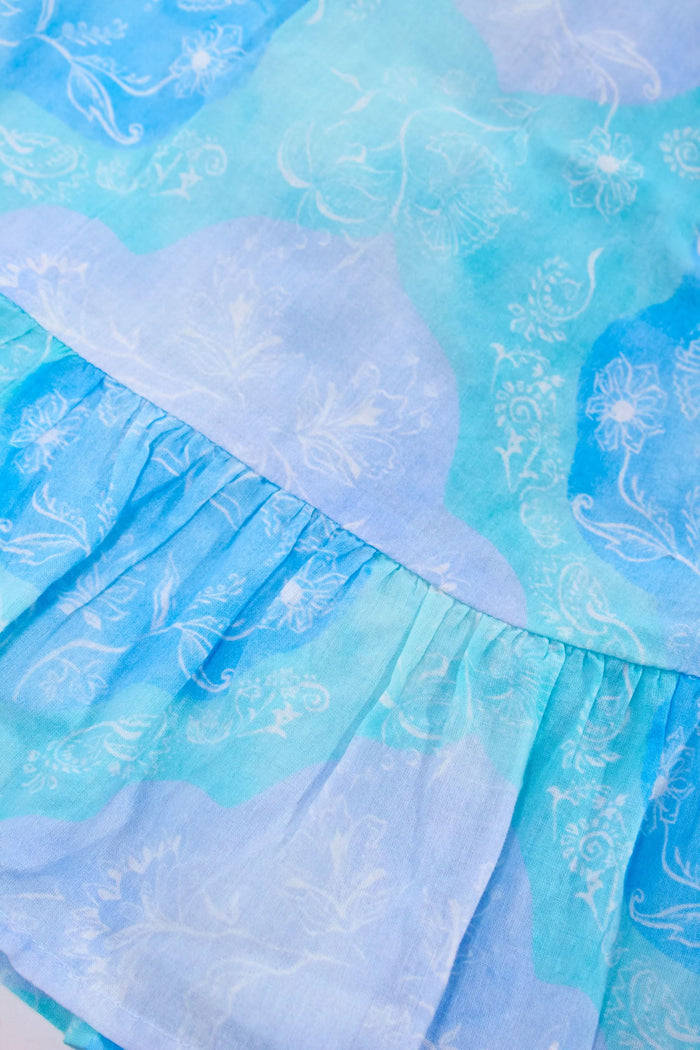 Close-up of light blue fabric with white and blue floral pattern and ruffled seam—ideal for the Samira Alicia Dress or any cotton voile minidress in a charming blue and green print.