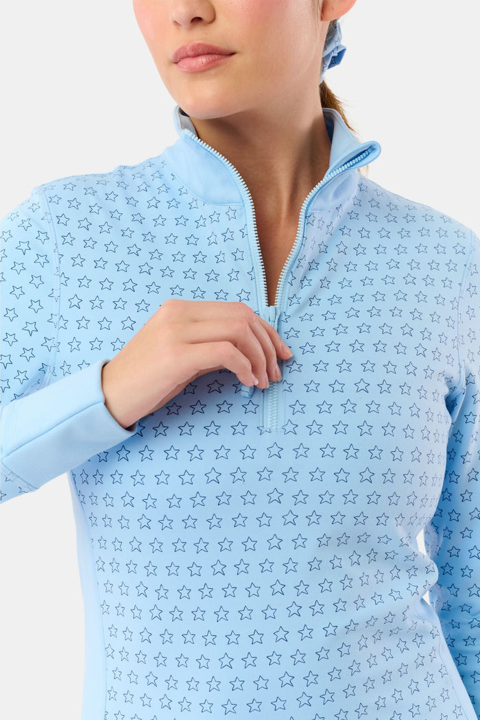 A woman wears the Roller Rabbit Stars Celia Quarter Zip in sky blue with a subtle star pattern and matching blue leggings, standing against a plain white background.