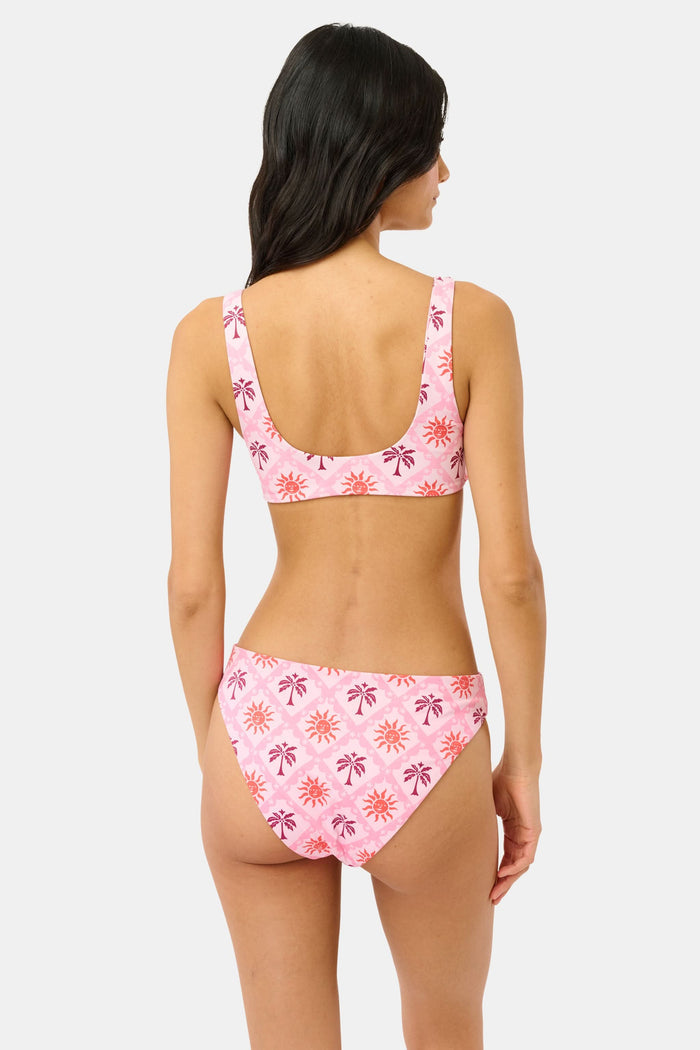 A model wears the Roller Rabbit Sunny Days Shelly Bikini Bottom, featuring orange and purple sun and palm tree patterns, shown from mid-torso to upper thigh against a plain background.